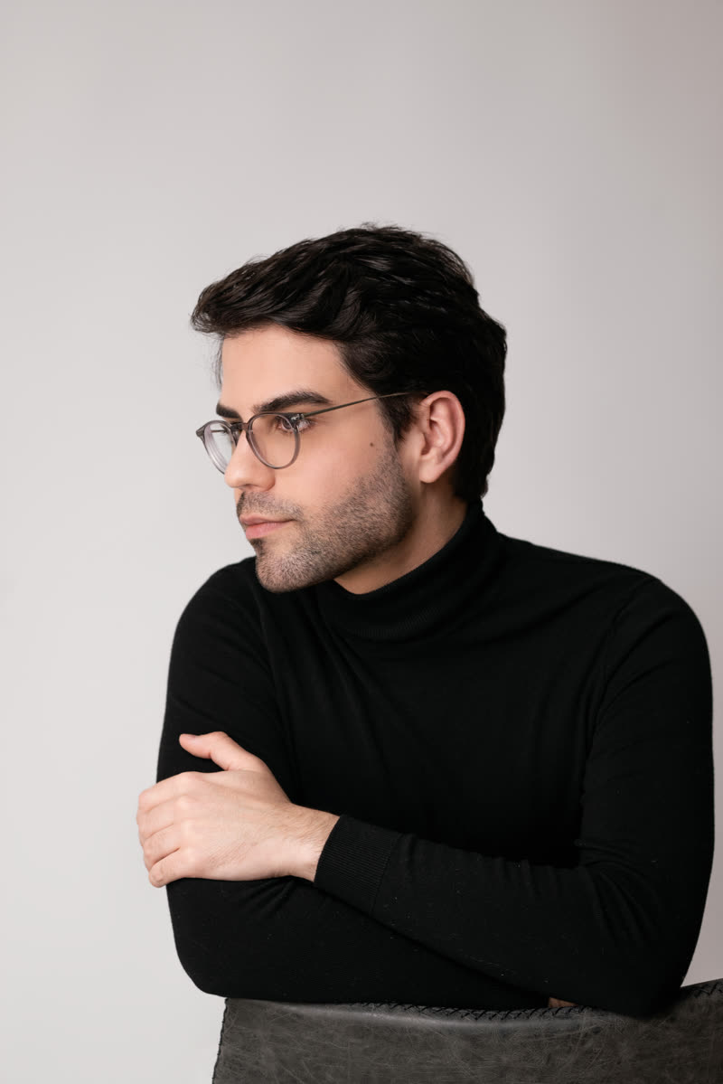 Lucas Bulcão, de blusa preta de gola alta, em retrato de estúdio